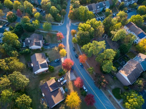 Aerial view of a suburban neighborhood with colorful autumn trees lining the streets and houses.