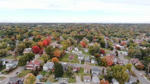 Aerial view of a suburban neighborhood with colorful autumn trees and houses, showcasing vibrant fall foliage.