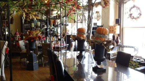 A cozy dining area decorated with autumn-themed arrangements, pumpkins, and warm lighting.