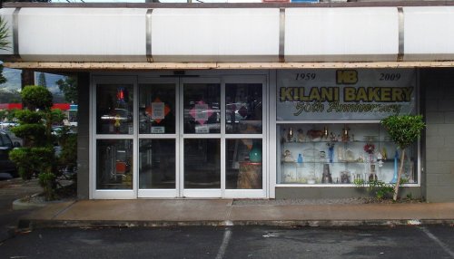 Exterior view of Kilani Bakery, featuring glass display cases and a sign celebrating its 50th anniversary.