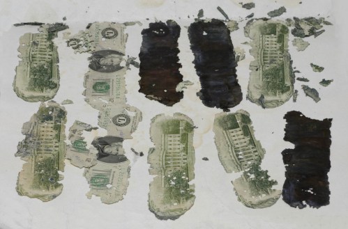 Faded and damaged currency notes arranged in a row on a textured surface, with dark patches and peeling edges.