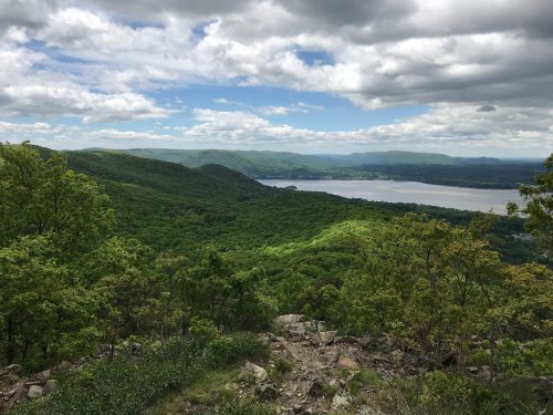 A scenic view of lush green hills and a river under a partly cloudy sky.