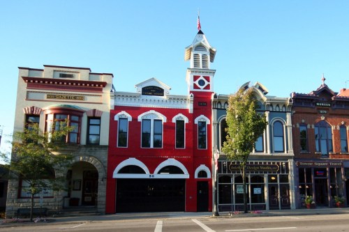 Historic buildings with unique architectural styles, featuring red accents and decorative details, line a street.