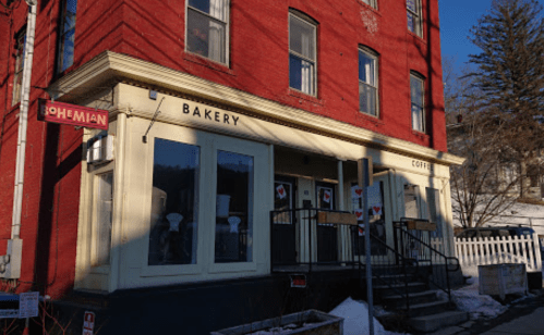 A red brick building with a sign reading "Bohemian Bakery" and "Coffee," featuring large windows and a staircase.