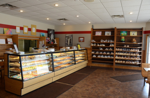 A cozy bakery interior featuring a display case filled with pastries and a wooden shelf with baked goods.
