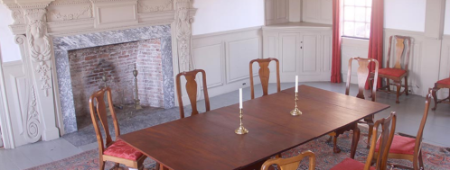 A spacious dining room featuring a wooden table, chairs, and a brick fireplace with decorative molding.