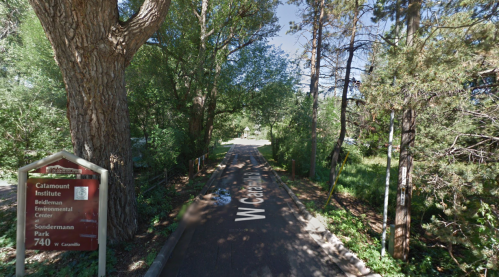A tree-lined path leads to a sign for the Claremont Institute and Sondermann Park, surrounded by greenery.