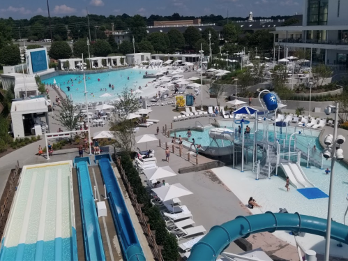 Aerial view of a water park featuring pools, slides, and sun loungers with people enjoying the facilities.
