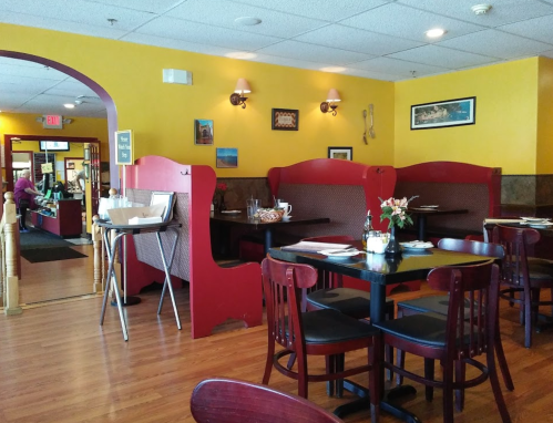 Cozy restaurant interior with red booths, wooden tables, and yellow walls, creating a warm dining atmosphere.