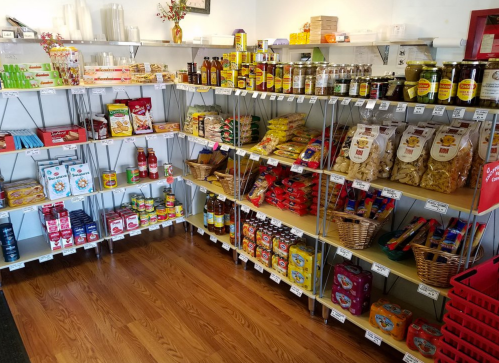 A well-stocked grocery store aisle featuring shelves of various packaged foods, sauces, and snacks.