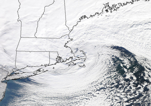 Satellite image showing a winter storm over the northeastern U.S., with clouds and swirling patterns off the coast.