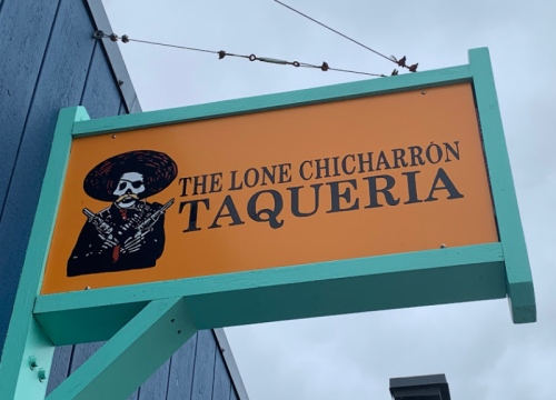 Sign for "The Lone Chicharrón Taqueria" featuring a skeleton in a sombrero holding two guns.