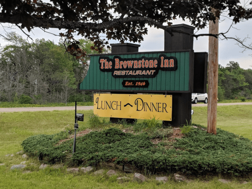 Sign for The Brownstone Inn restaurant, established in 1946, advertising lunch and dinner services. Green and black design.