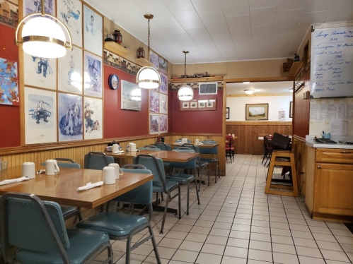 Cozy diner interior with wooden tables, teal chairs, and colorful wall art, creating a warm, inviting atmosphere.
