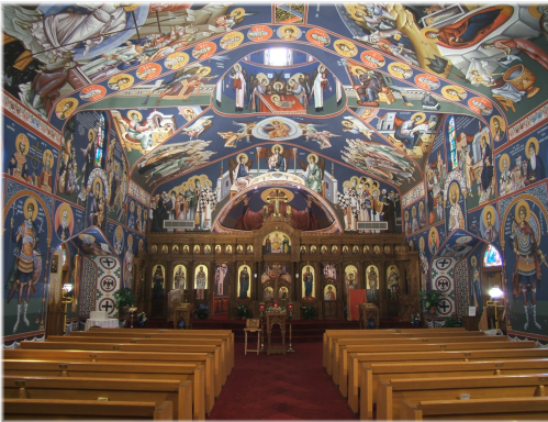 Interior of a beautifully decorated church with vibrant frescoes, wooden pews, and an ornate altar.