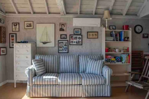 Cozy living room with a striped sofa, framed photos on the walls, and a bookshelf filled with books and decor.