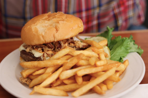 A plate with a burger topped with cheese and crispy onions, served with a side of golden French fries and lettuce.
