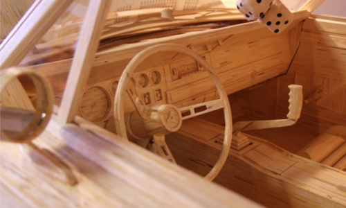Detailed model of a car interior crafted from wooden sticks, featuring a steering wheel and gear shift.