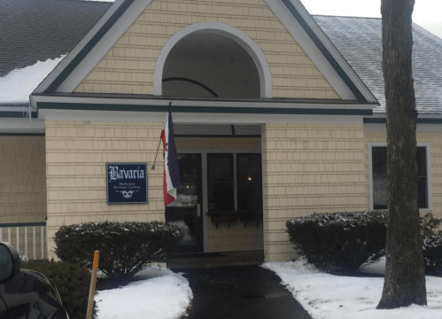 A snowy exterior view of a building with a sign reading "Bavaria" and a flag hanging by the entrance.
