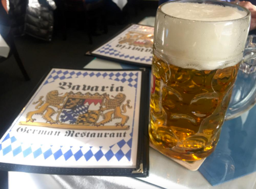 A frothy beer mug next to a menu for Bavaria German Restaurant, featuring a blue and white checkered design.