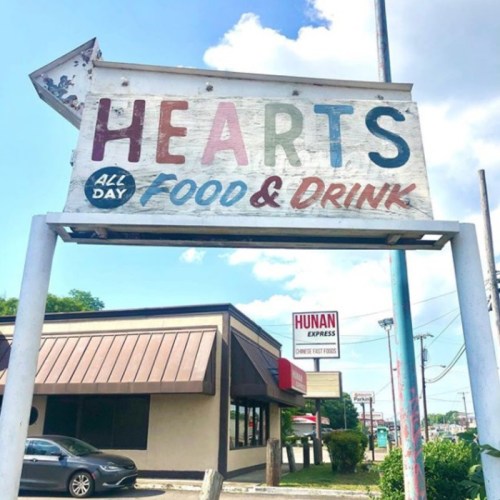 Sign for "Hearts Food & Drink" with colorful letters, located near "Hunan Express" restaurant on a sunny day.