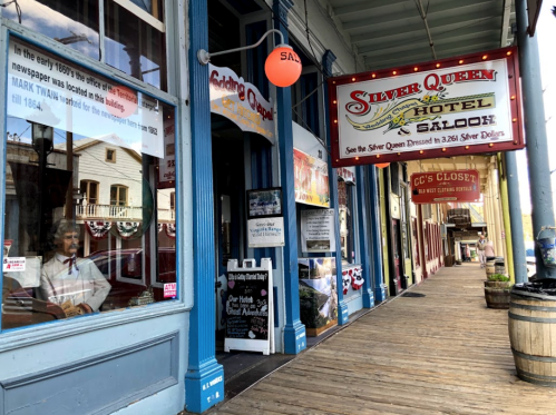 Historic storefronts of the Silver Queen Hotel and Saloon, featuring colorful signage and wooden walkways.