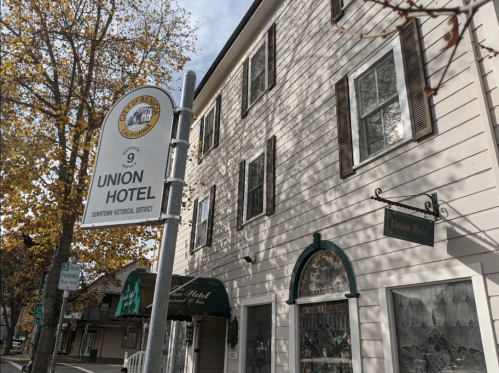 Sign for Union Hotel in a historic downtown area, with a charming building and autumn leaves in the background.