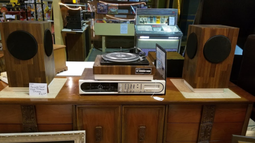 A vintage audio setup featuring a turntable and speakers on a wooden table in a retro shop.