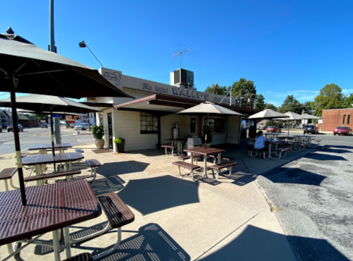 Exterior view of Wally's, featuring outdoor seating under umbrellas and a clear blue sky.