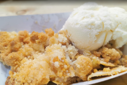 A serving of warm dessert with crumbled topping next to a scoop of vanilla ice cream.