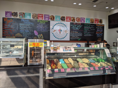 A colorful ice cream shop interior featuring a display case of various ice cream flavors and a menu on the wall.