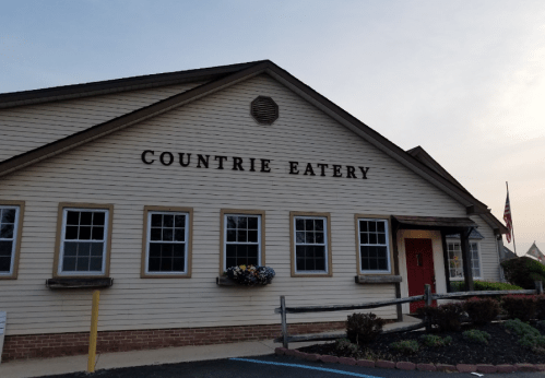 Exterior of a restaurant named "Countrie Eatery," featuring a wooden facade and flower boxes under the windows.