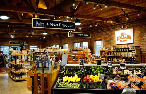 Interior of a market featuring fresh produce, dry goods, and various local products on display. Warm, inviting atmosphere.