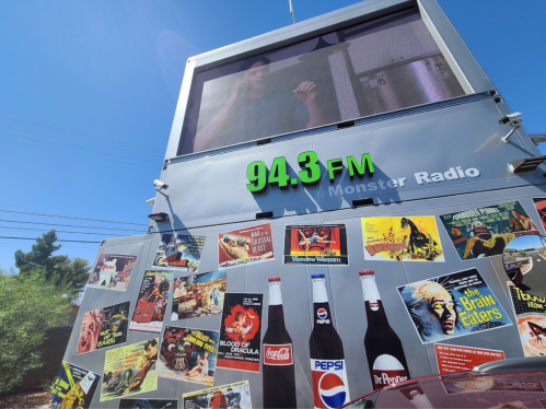 A large billboard displays a video and vintage movie posters, with "94.3 FM Monster Radio" prominently featured.