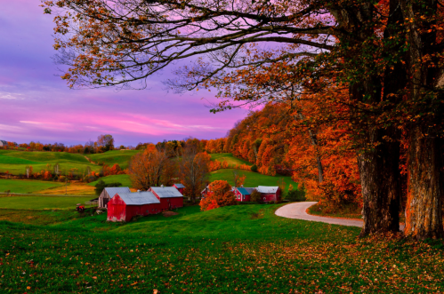 A scenic autumn landscape featuring red barns, vibrant fall foliage, and a winding road under a colorful sky.