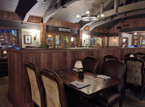Cozy restaurant interior with wooden walls, elegant seating, and soft lighting, creating an inviting atmosphere.