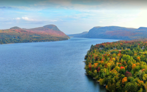 A serene lake surrounded by mountains and vibrant autumn foliage under a clear blue sky.
