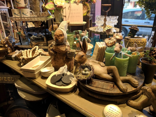 A whimsical display of decorative items, including a rabbit, a bear figurine, and various vintage trinkets on a table.