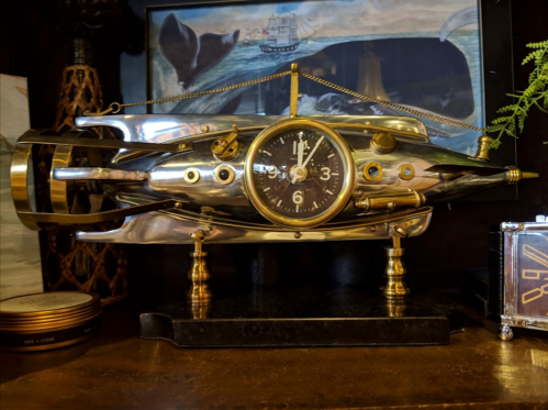 A decorative clock designed to resemble a vintage submarine, featuring metallic details and a classic clock face.