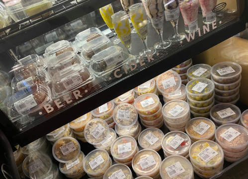 A display case filled with various desserts and snacks in clear containers, labeled with beer, cider, and wine options.