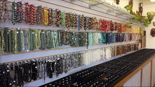 A display of colorful beaded necklaces hanging on a wall, with various strands organized on a table below.