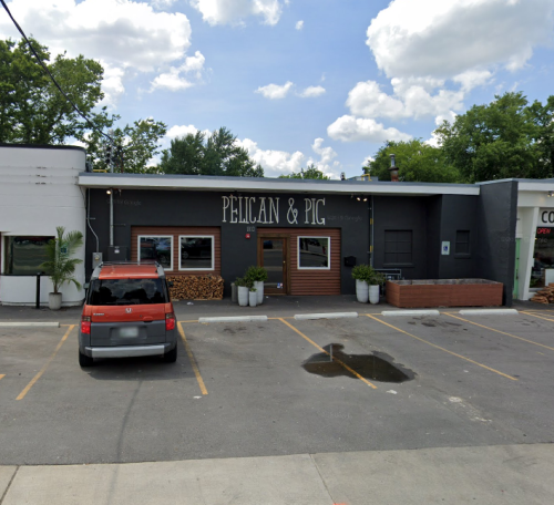 Exterior of a restaurant named "Pelican & Pig," featuring a modern design and parked cars in front.