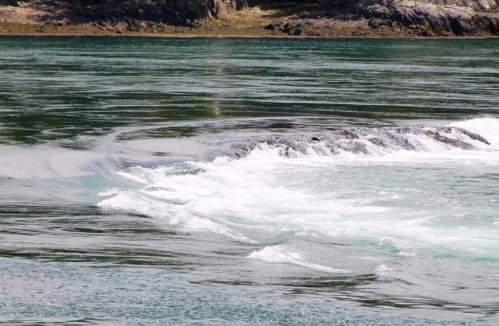 Waves gently lap against rocky shores in a serene, turquoise water landscape.