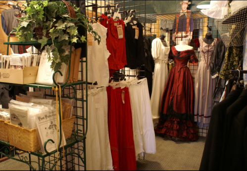 A vintage clothing store display featuring various dresses and patterns on racks and shelves.