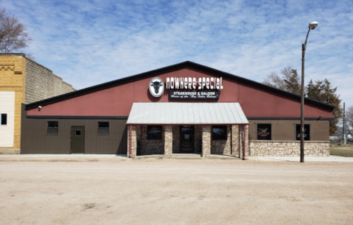 Exterior of "Nowhere Special Steakhouse & Saloon," featuring a red and brown building with a stone facade and clear sky.