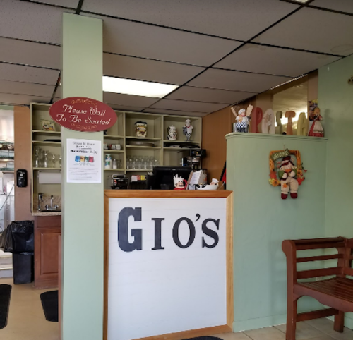 Interior of Gio's restaurant featuring a reception area, counter, and decorative figures on the walls.
