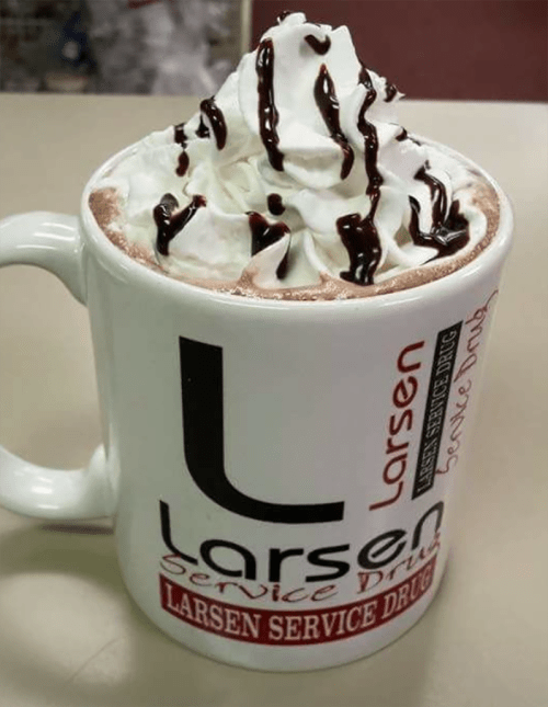 A large mug filled with hot chocolate topped with whipped cream and drizzled with chocolate syrup.