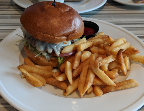A juicy burger with melted cheese, lettuce, and tomato, served with a side of golden French fries and ketchup.