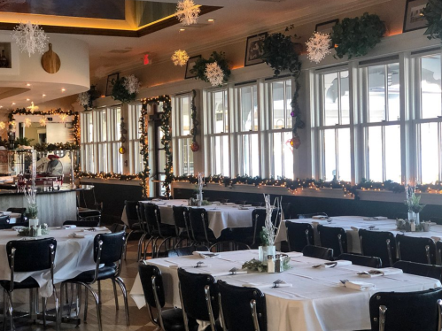 A festive restaurant interior with decorated windows, tables set for dining, and holiday decorations throughout.