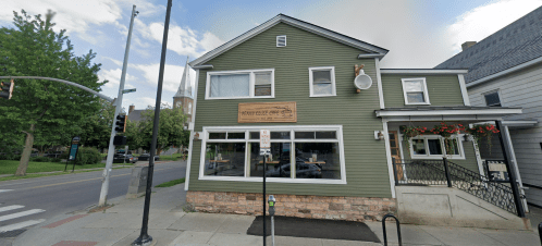 A green two-story building with a sign reading "Heavy Metal Cafe," located at a street corner with trees nearby.